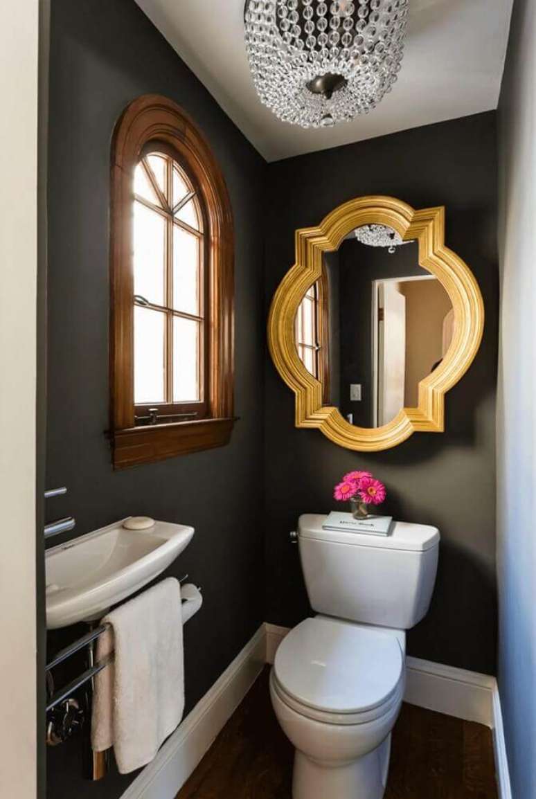 38. Decoração de lavabo pequeno com parede preta e espelho dourado