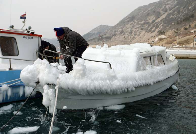 Homem limpa barco que ficou coberto de gelo na Croácia