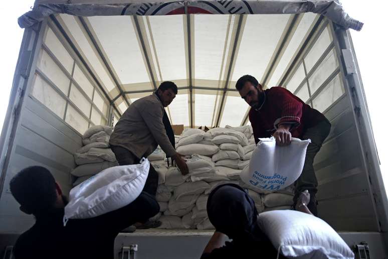 Homens descarregam suprimentos de caminhão na cidade de Ghouta