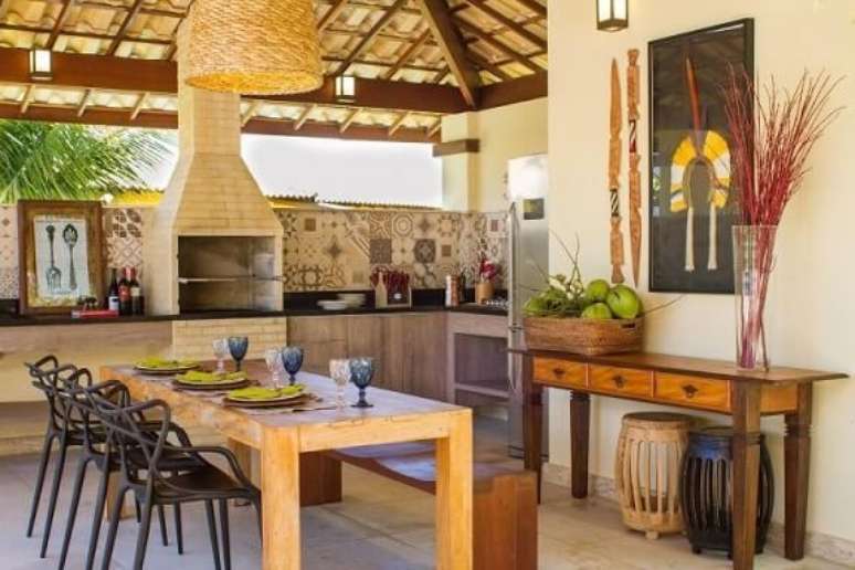 27. A decoração com madeira, tijolinhos e tons terrosos dá um ar rústico à varanda gourmet. Projeto de Jamile