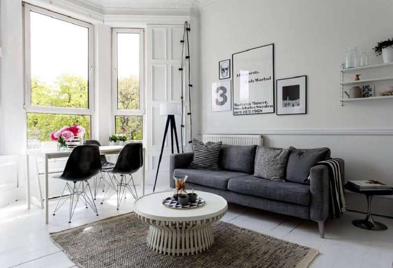 31. Linda decoração de sala neutra com sofá cinza e cadeiras pretas.