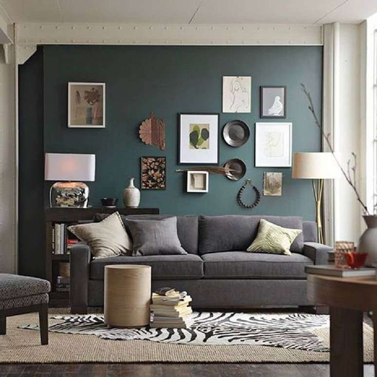 50. Decoração de sala com parede verde e muitos quadros.