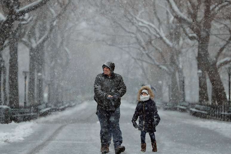 Homem e criança andam pelo Central Park, em Nova York, durante tempestade de neve.