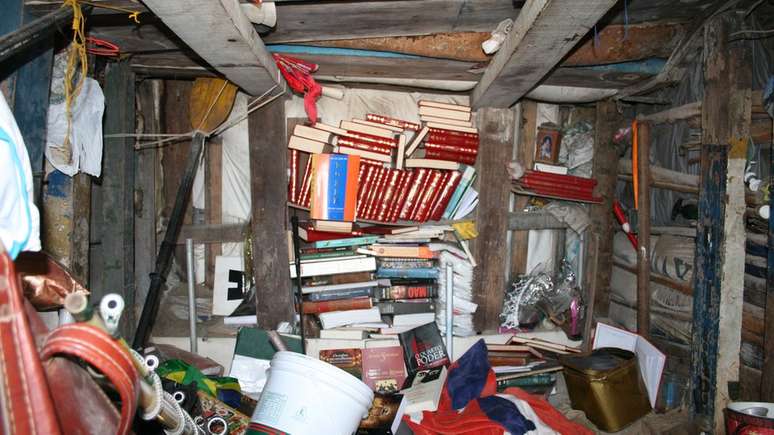 Escultor aprendeu a ler sem ir à escola e guarda vários livros no abrigo que construiu sob o castelo de areia | Foto: Adriana Stock/BBC Brasil