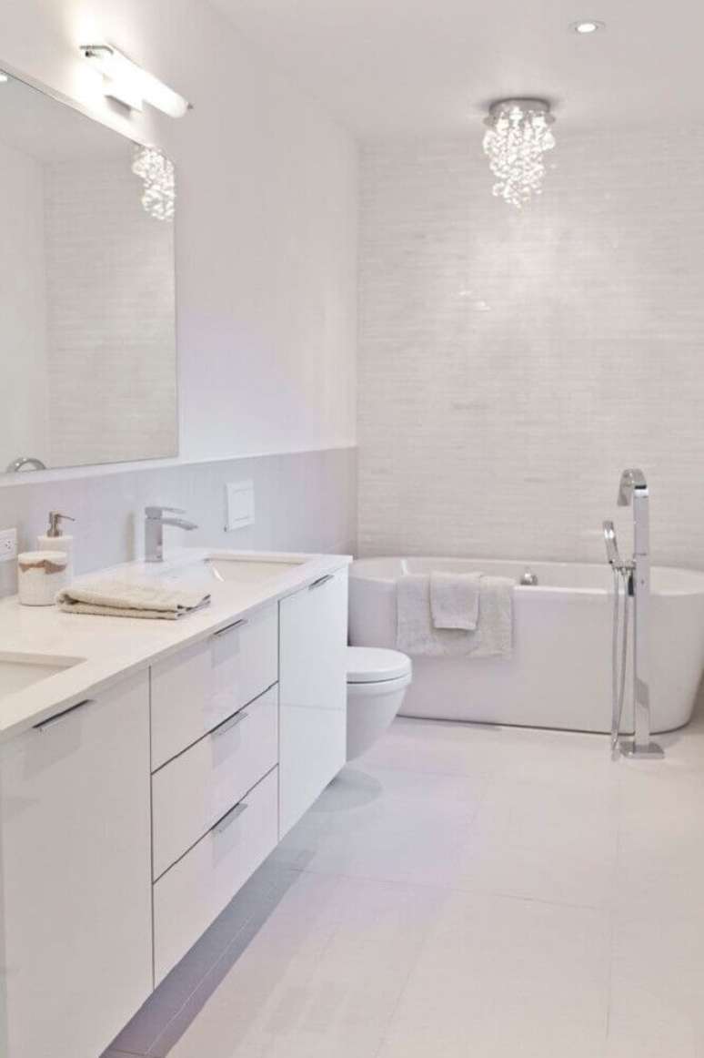 40. Banheiro todo branco com banheira e pequena luminária sofisticada