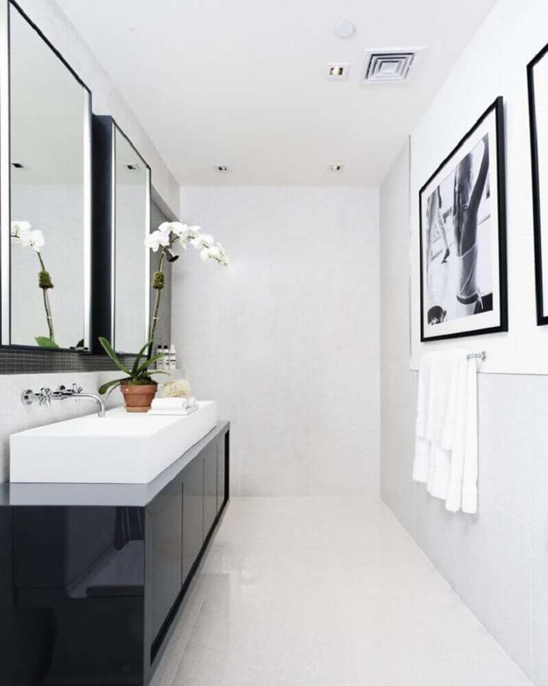 58. Banheiro preto e branco minimalista com gabinete preto e quadros na parede