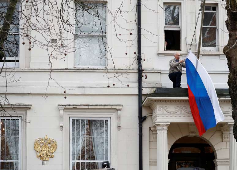 Homem recolhe a bandeira da Rússia da embaixada em Londres