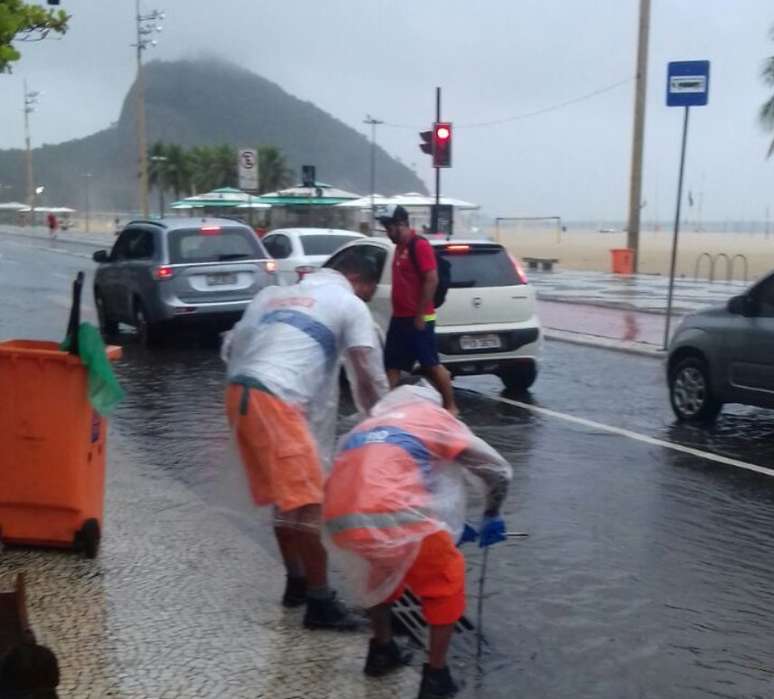 Homens trabalham para escoar bolsão d'água na Avenida Atlântica com Avenida Princesa Isabel, em Copacabana