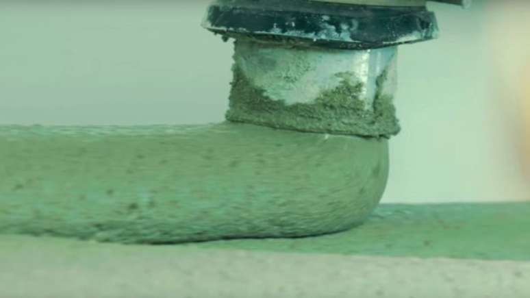 O material semelhante a uma argamassa sai de uma esp&eacute;cie de mangueira e vai formando a casa em camadas. (Imagem: New Story)