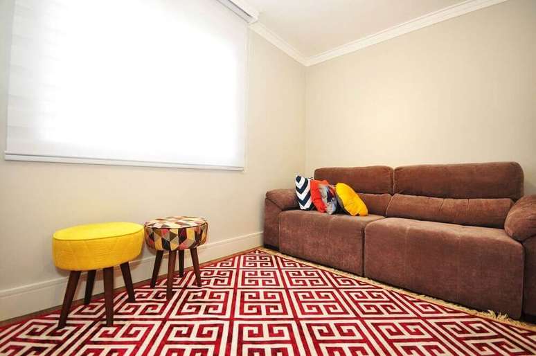 24. Decora&ccedil;&atilde;o de sof&aacute; marrom com almofadas coloridas e tapete vermelho