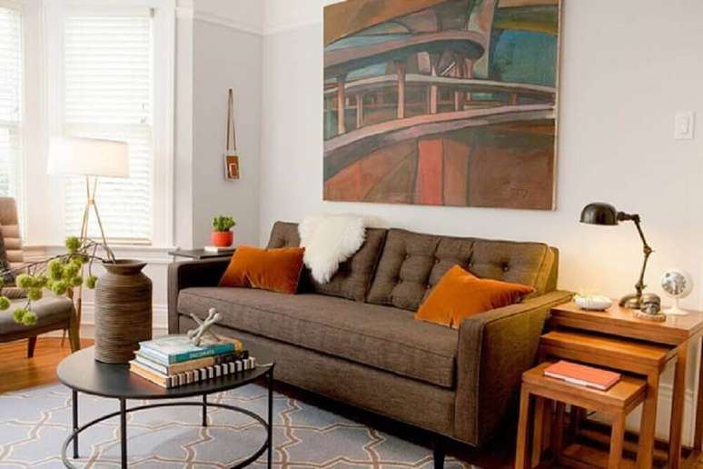 8. O laranja é um tom que contrasta bastante com o sofá marrom com almofadas
