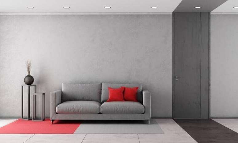 2. Decoração de sala com parede cinza com tonalidades diferentes e almofadas vermelhas.