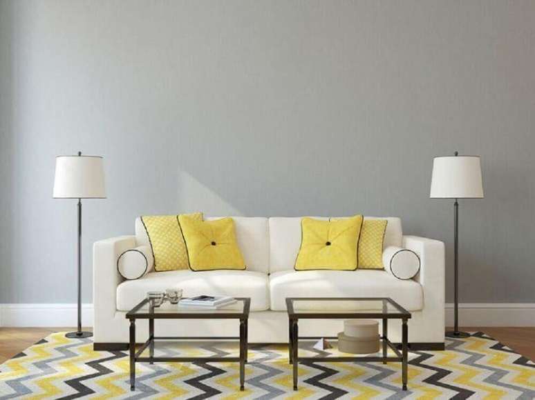 32. Sala com parede cinza almofadas amarelas e tapete geométrico