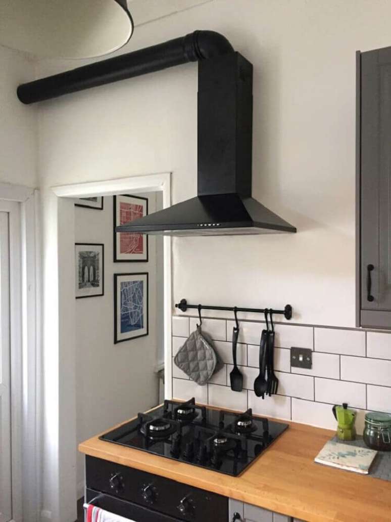 12. Decoração no estilo minimalista em cozinha com coifa de parede preta.