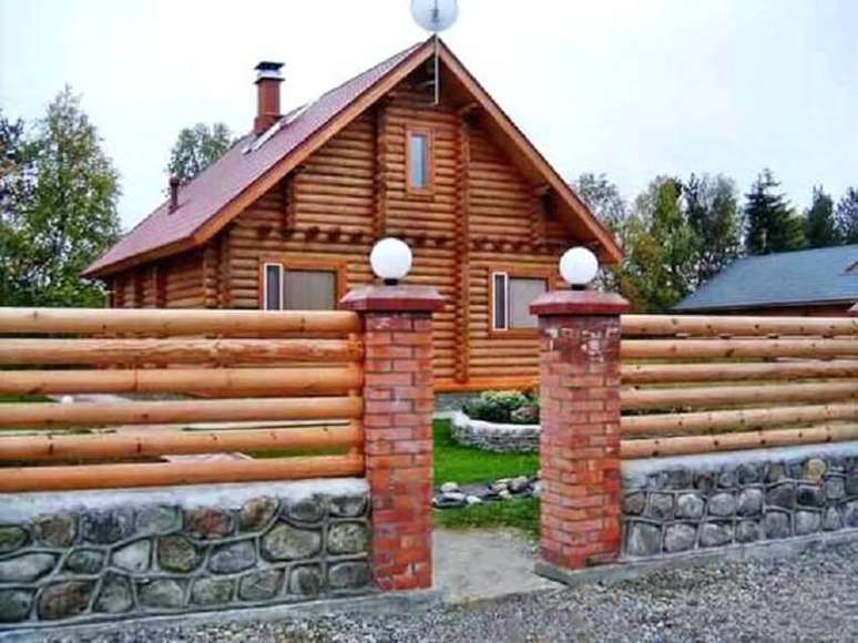 31. Essa casa recebeu uma fachada com mix de materiais como madeira para a cerca, pilastras de tijolinho e base de pedra