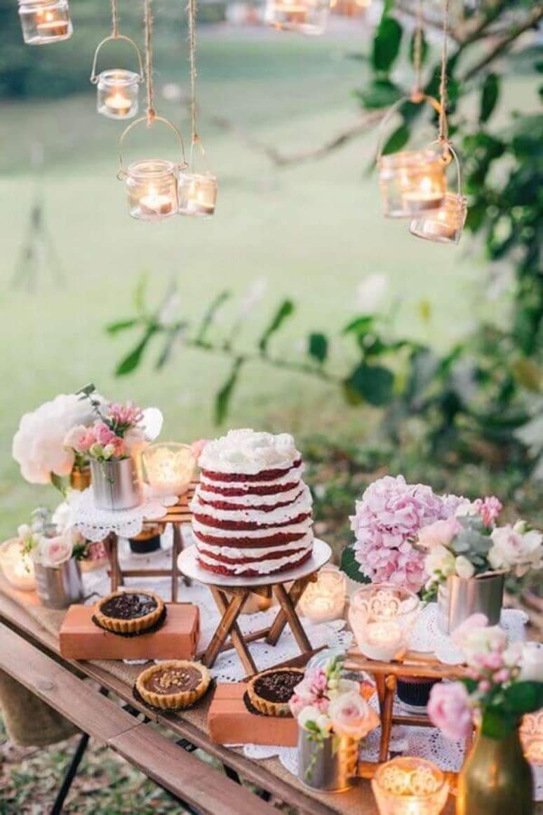 40. Decoração de mesa de casamento com bolo red velvet e luminárias suspensas