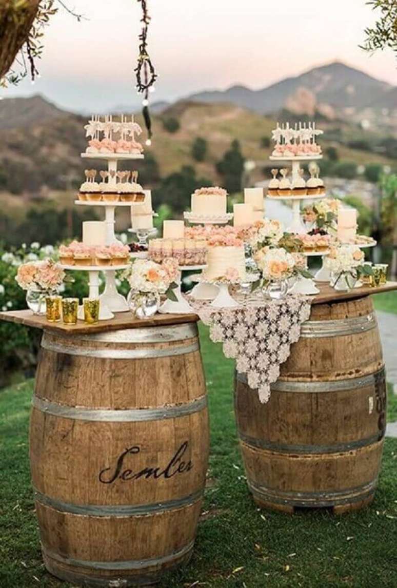 9. Decoração de mesa de casamento no campo com suporte de barris e detalhes delicados.