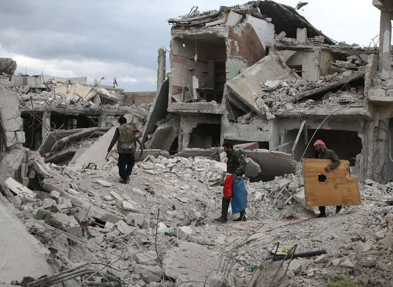 Pessoas caminham sobre destroços de prédios em Douma 30/03/2018 REUTERS/Bassam Khabieh