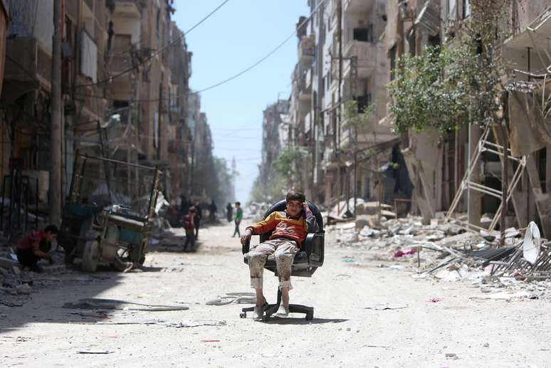 Menino em rua destruída na cidade síria de Douma 
 16/4/2018    REUTERS/Ali Hashisho 