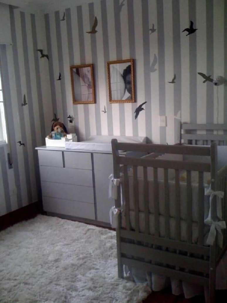 24. Quarto de bebê com decoração em tons de cinza e com papel de parede listrado com desenhos de pássaros