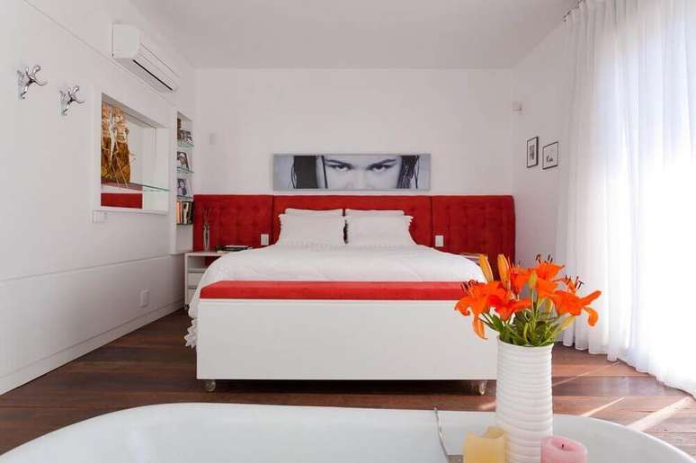 11. O grande destaque da decoração clean para o quarto foi a cabeceira estofada casal em um vermelho bem vibrante