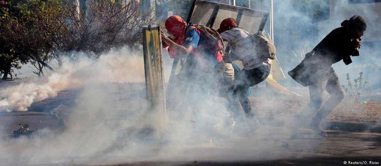 Manifestantes em meio a nuvem de gás lacrimogêneo em Manágua
