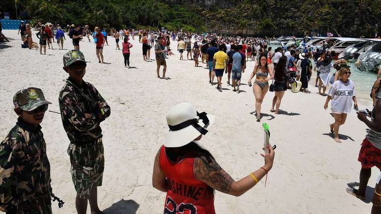 Guardas monitoram turistas em Maya Beach, na Tailândia, antes do banimento