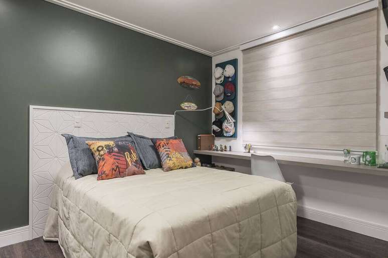 16. Essa decoração de quarto jovem masculino recebeu um porta bonés e bastante almofadas na cama