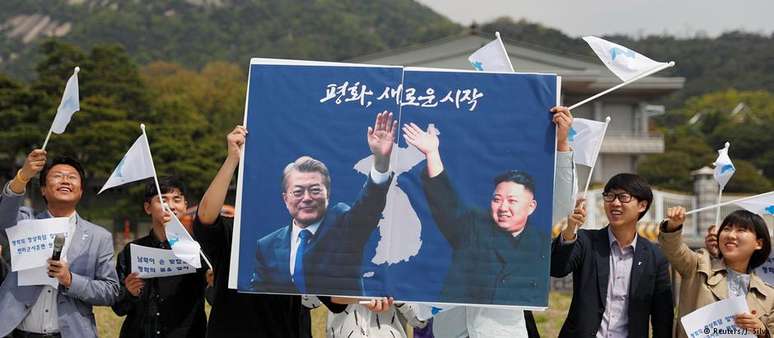 Estudantes erguem cartaz com os líderes das duas Coreias em ato de apoio à aproximação entre os dois países em Seul