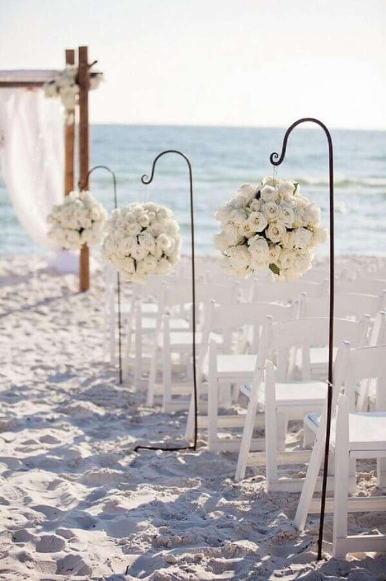 19. Linda decoração com arranjos de rosas brancas para a cerimônia de noivado na praia