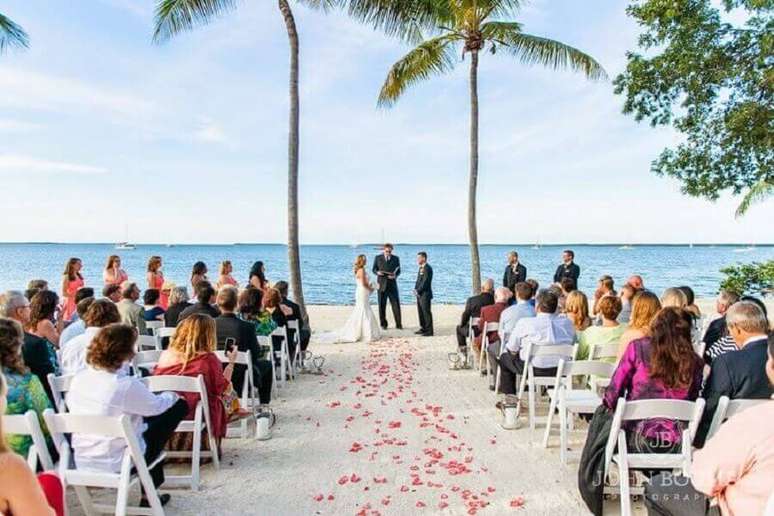 3. Casamento na praia simples onde a &uacute;nico item decorativo s&atilde;o as p&eacute;talas de flores no caminho dos noivos.