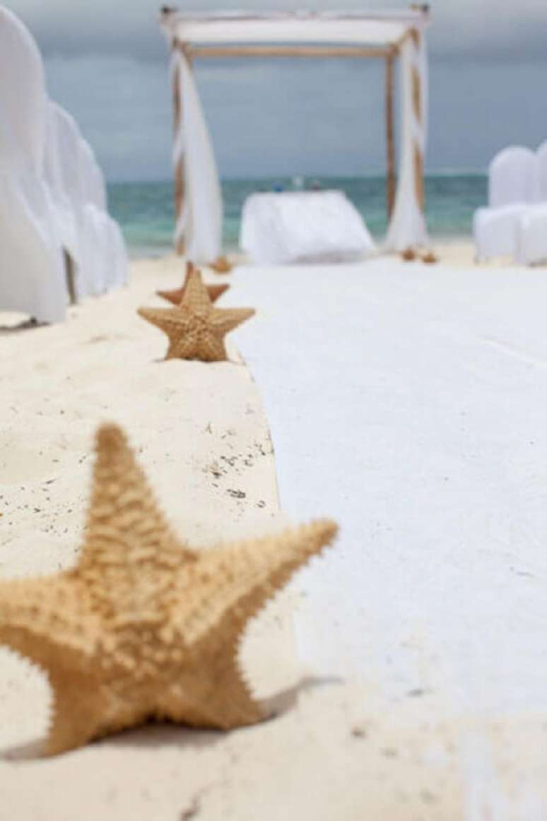 6. Fotos de casamento na praia com decoração com estrelas do mar no caminho para o altar