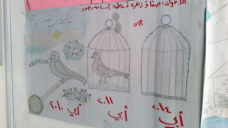 A legenda na parte superior do desenho diz: "Irmãos: Safa, Zahra, Fatima, Osama, Joud". A legenda na parte inferior do desenho diz (da esquerda para a direita): "Meu pai em 2010", "Meu pai em 2011", "Meu pai em 2014".