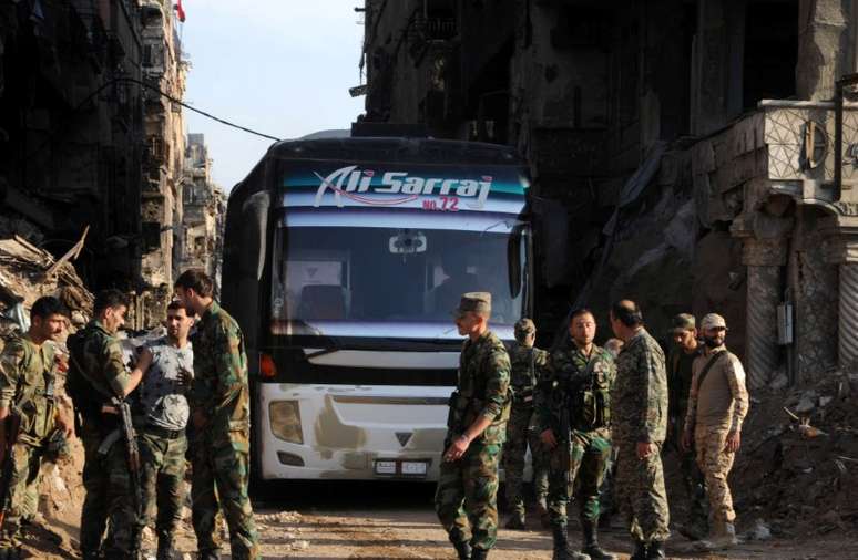 Soldados leais ao presidente sírio, Bashar al-Assad, perto de ônibus transportando rebeldes do campo de Yarmouk 30/04/2018 SANA/Divulgação via REUTERS