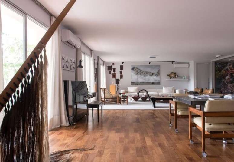 38. Aqui, para repartir os ambientes, os pisos para sala de madeira são divididos por um tapete. Projeto de AMC Arquitetura