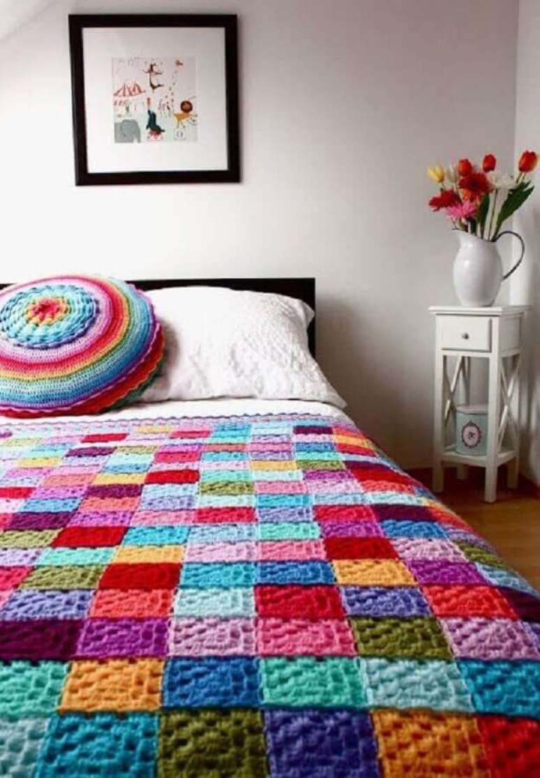 22. Decoração com almofada de crochê redonda e colorida combinando com a colcha da cama
