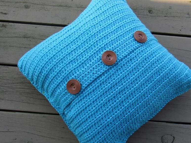 33. Os botões na capa de almofada de crochê azul ganhou bastante destaque deixando-a ainda mais bonita
