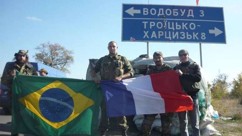 Lusvarghi (esq.) posa com a bandeira brasileira ao lado de rebeldes pr&oacute;-R&uacute;ssia, em 2014