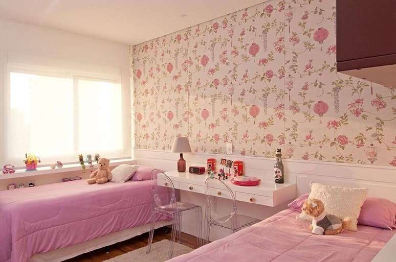 22. Aqui a decoração de quarto infantil feminino ficou super delicada e atual com o papel de parede com estampa floral e as cadeiras de acrílico transparente