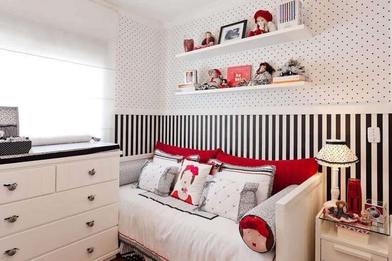 35. Essa decoração de quarto infantil feminino ficou muito moderna com as cores em preto, branco e vermelho e o papel de parede listrado e de poás