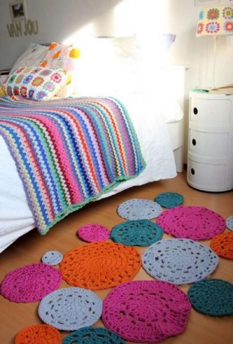 36. Colcha de crochê colorida em quarto com tapete de crochê