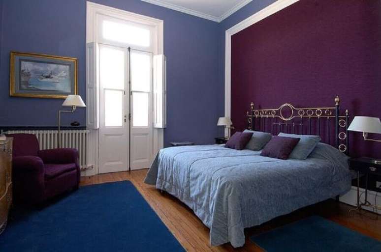 53. Decoração de quarto de casal com parede roxa e tapete azul