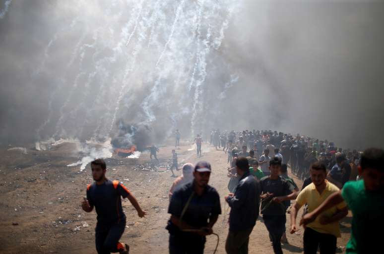 Manifestantes palestinas correm de gás lacrimogêneo lançado por forças israelenses na fronteira entre Gaza e Israel
14/05/2018 REUTERS/Mohammed Salem 