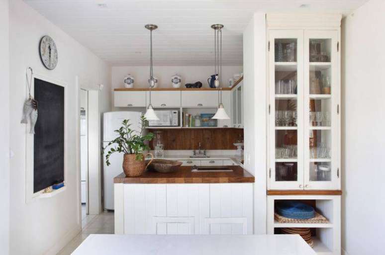 22. A cor branca no ambiente e no balcão de cozinha deixa a cozinha americana planejada mais iluminada