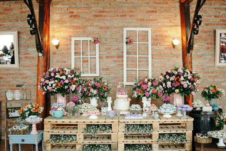 15. Mesa de bolo com arranjos de flores coloridos, pallets em madeira e iluminação especial