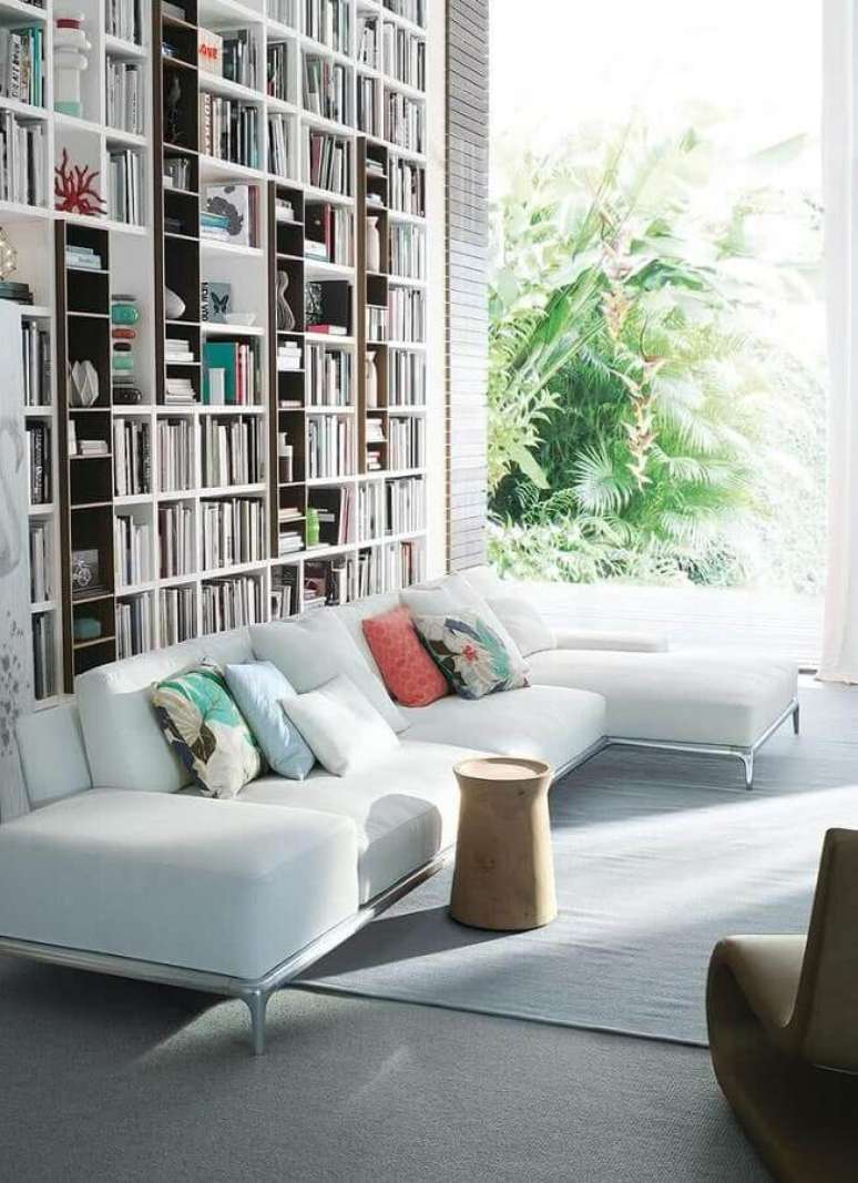 33. Linda sala decorada com estante de livros e com lindo e confortável sofá branco com chaise