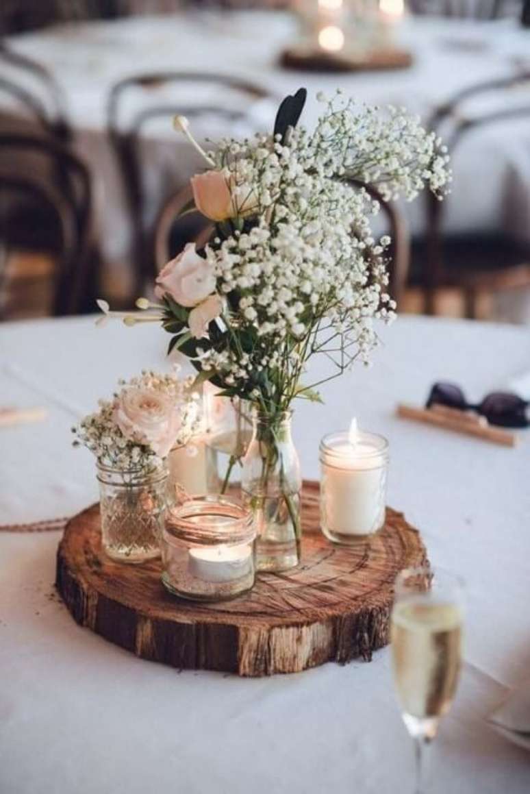 12. Centro de mesa de casamento rústico com base de madeira, velas e flores