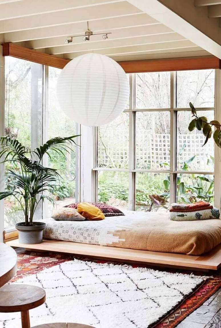 23. Lindo quarto com decoração bem leve com vasos de plantas, luminária e cama japonesa
