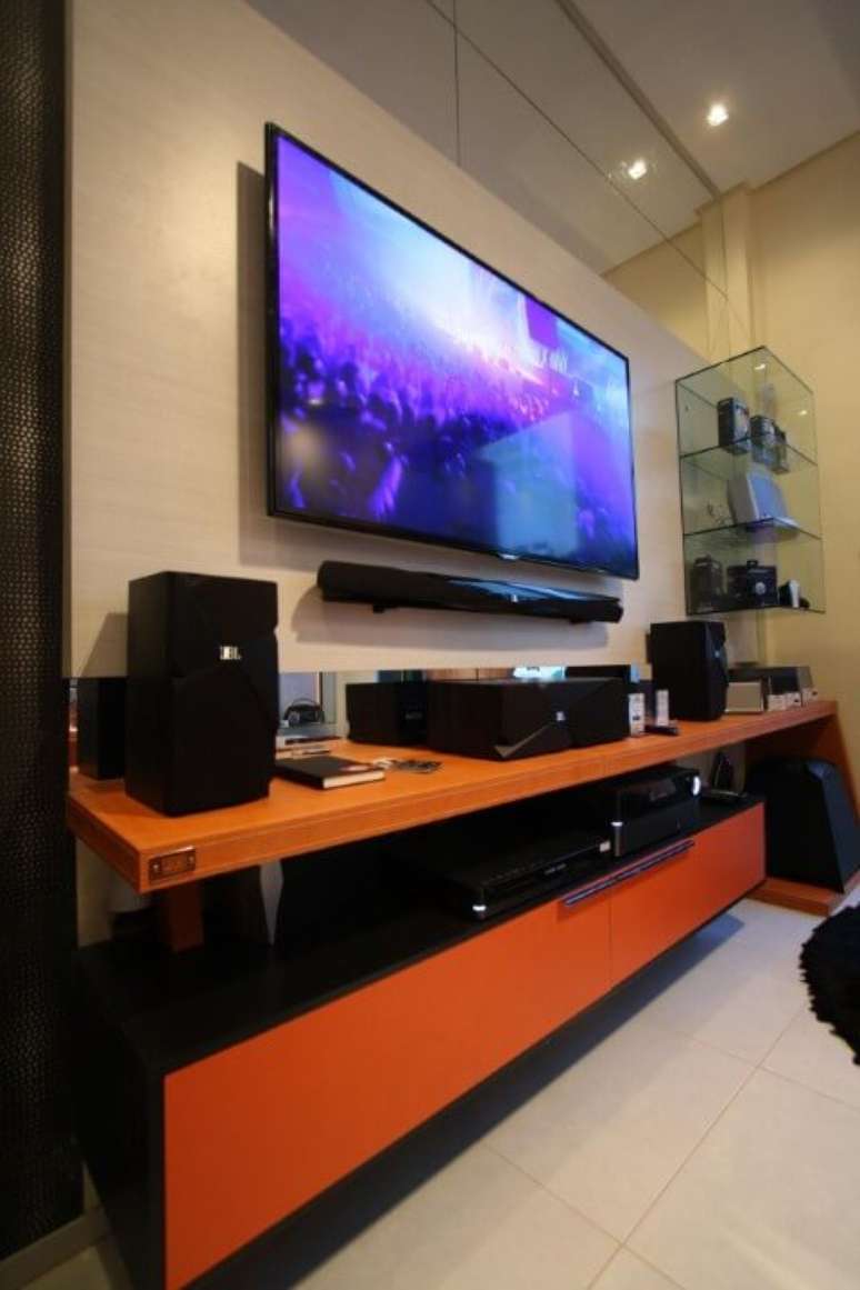 61. Rack para sala colorido com as cores laranja com preto e painel para TV bege. Projeto de Amaury Jr