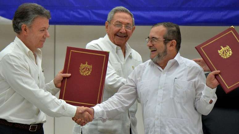 Juan Manuel Santos e Timochenko se cumprimentam, observados por Ra&uacute;l Castro: foi o fim do mais longevo conflito armado latino-americano